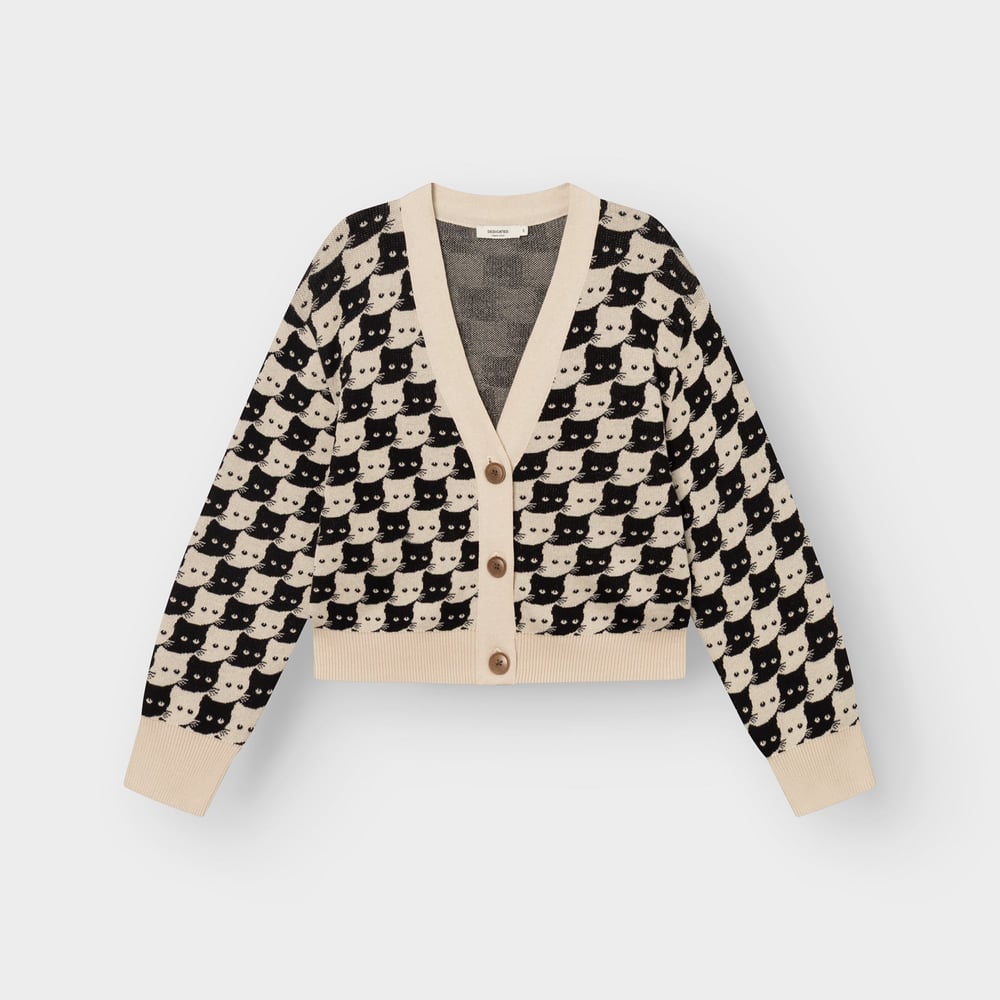 Studio shot of the Kanan cardigan in Oat White. This knitted V-neck is covered in a playful pattern of black and white cats.