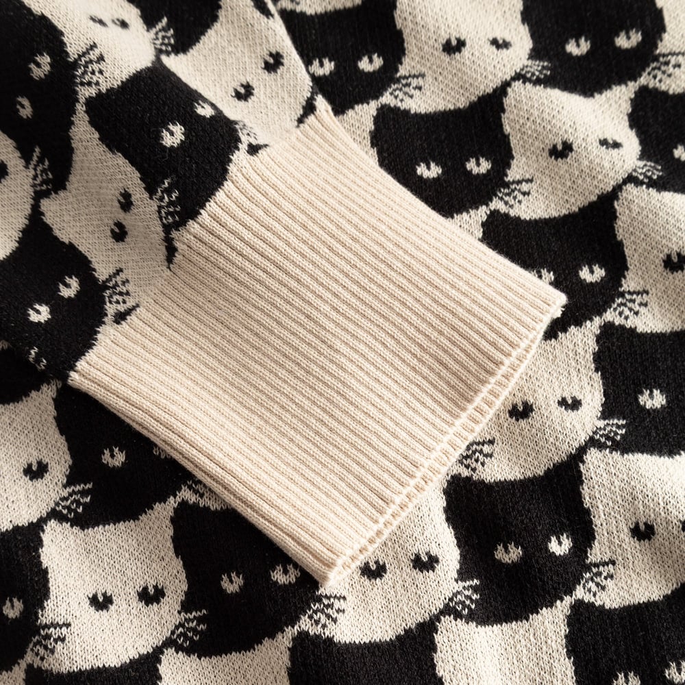 Close-up of the oat white ribbed cuff on the Cardigan Kanan, set against the playful black and white jacquard cat pattern.