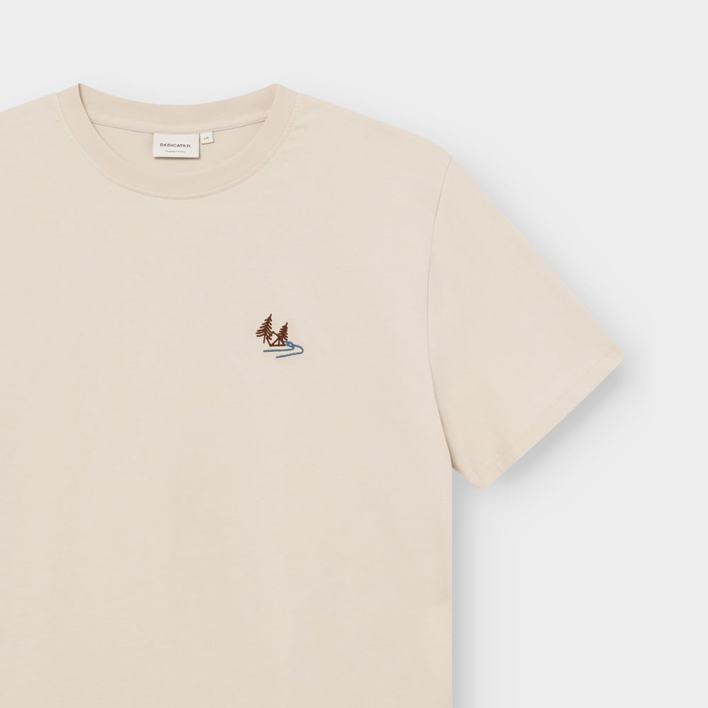 Close-up of the oat white T-shirt Stockholm Camp Creek, showing the detailed nature embroidery on the chest and brand label.
