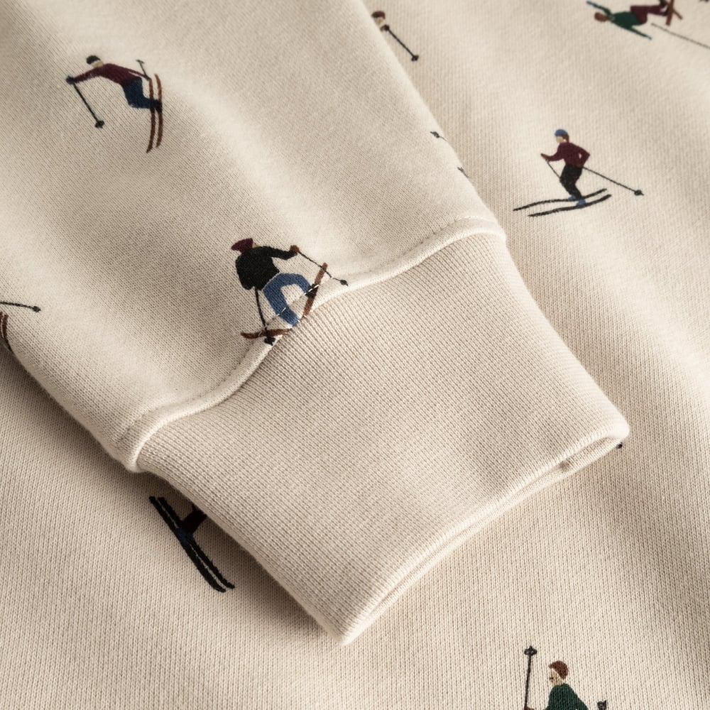 Close-up detail shot of the ribbed cuff and all-over skier print on the oat white Malmoe sweatshirt.