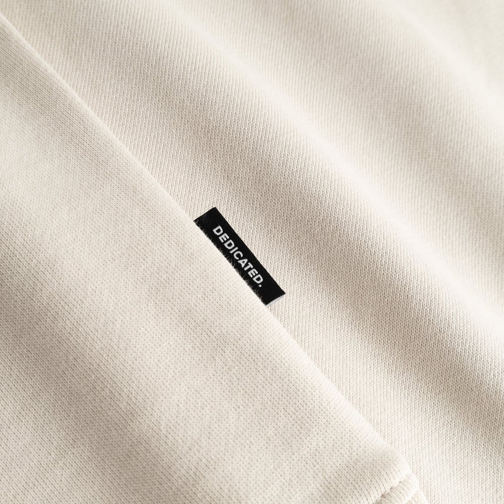 Close-up shot of the oat white Sweatshirt Malmoe, highlighting the soft fabric and the black Dedicated brand tag on the seam.