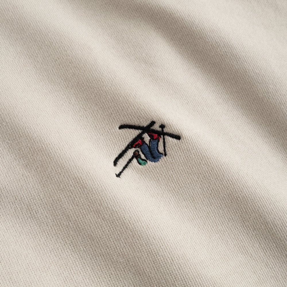 Close-up of the playful 'Ski Crash' embroidery on the chest of the Dedicated Sweatshirt Malmoe in oat white.