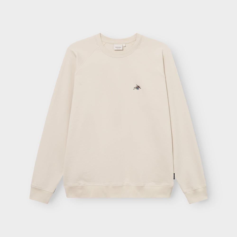 Front view of the oat white Sweatshirt Malmoe, laid flat, featuring a small, colourful 'Ski Crash' embroidery on the chest.