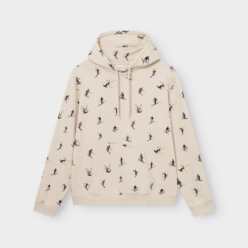 Studio shot of the oat white Falun Ski Team hoodie. The sweater has a fun all-over print of colorful skiers.