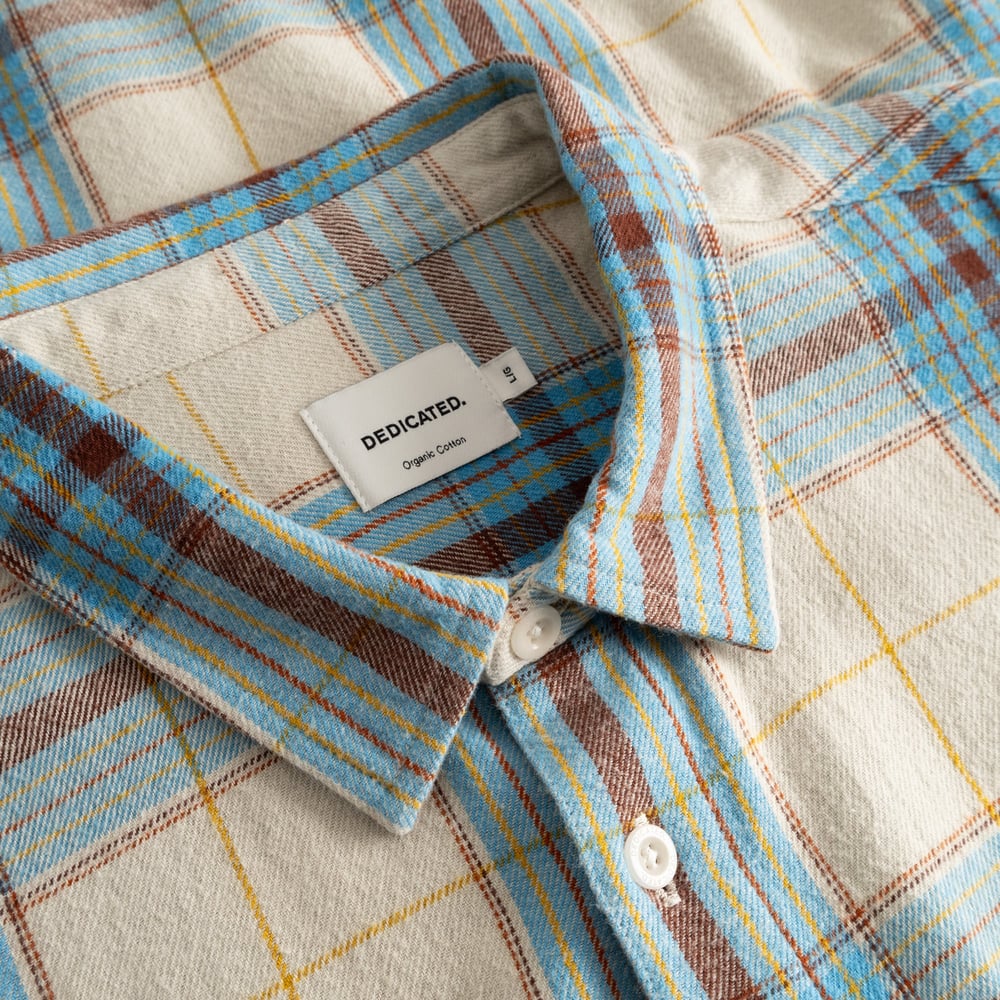 Gros plan sur le col de la chemise Rute Flannel, avec son motif tartan classique blanc avoine, bleu et marron.