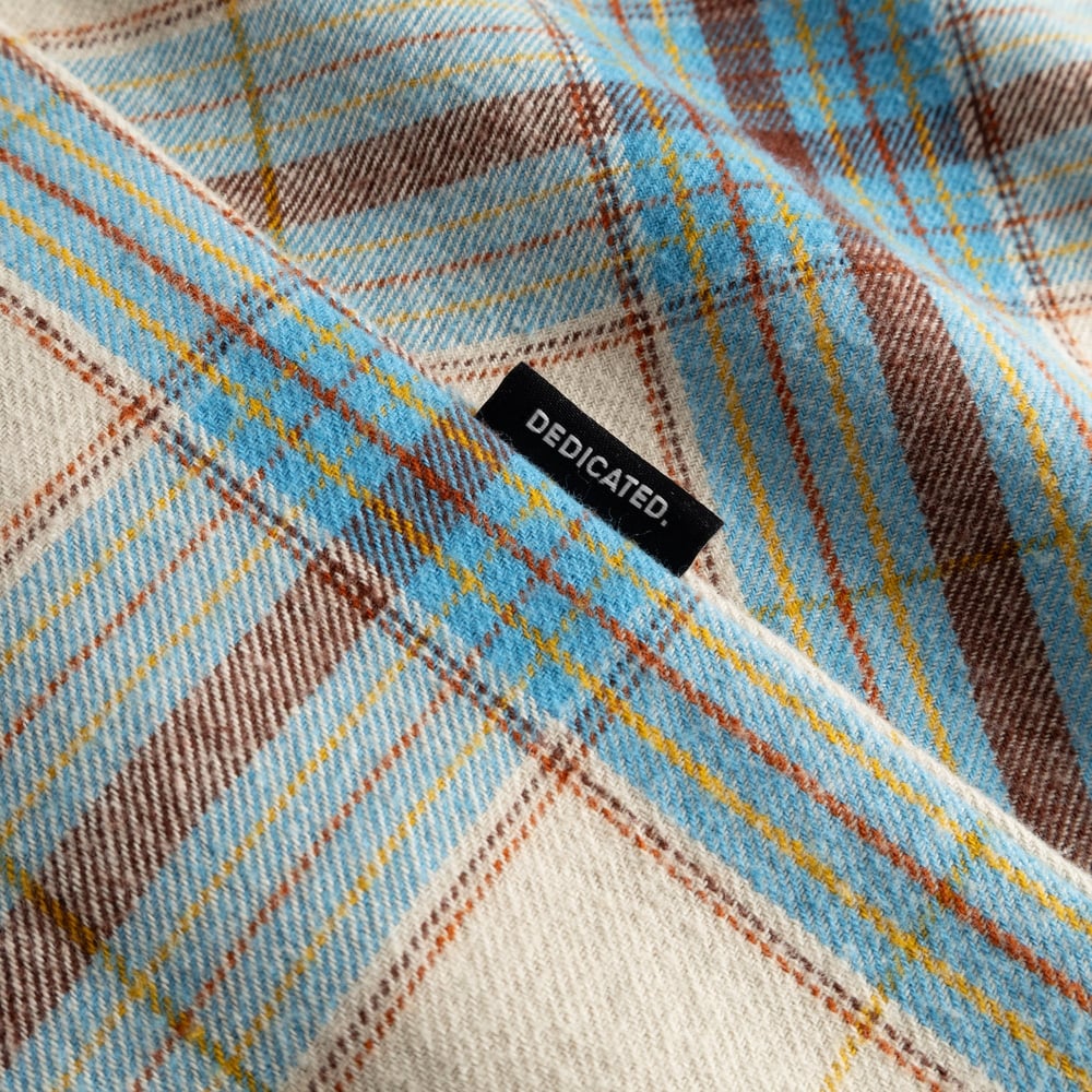 Gros plan sur la chemise Rute en flanelle Tartan Check Oat White, mettant en valeur son tissu doux et l'étiquette Dedicated.