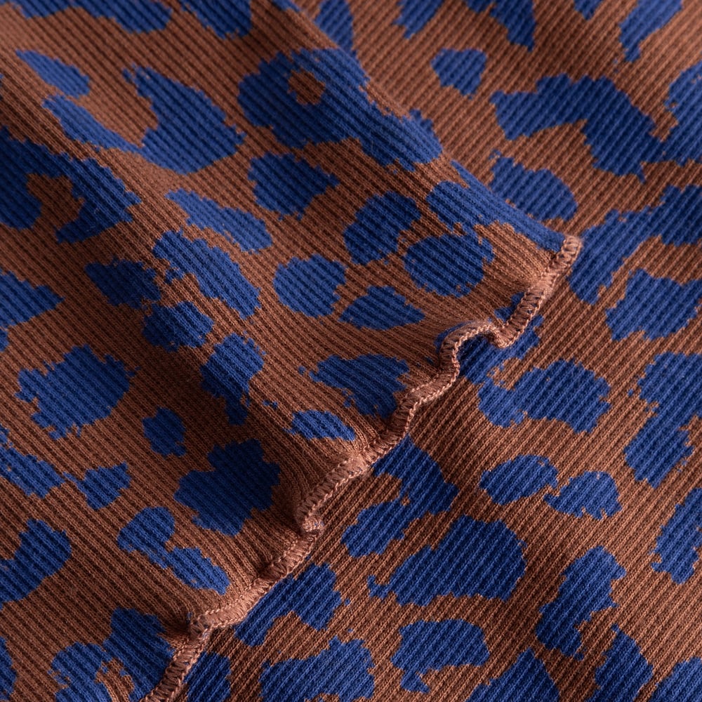 A close-up of the Rib Dress Lofta in a playful blue and brown leopard print, showing soft ribbed texture and lettuce seam.