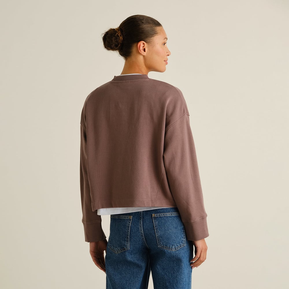 Back view of a woman wearing the Sweatshirt Gia in Sparrow Brown, showcasing its relaxed fit and dropped shoulders.