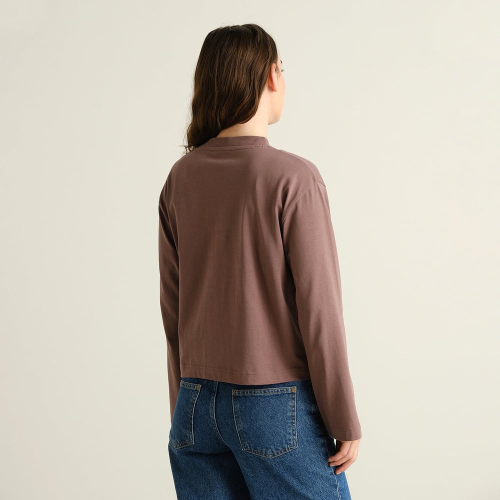 Model seen from the back, wearing the brown Vreta long-sleeved t-shirt with a pair of classic blue jeans.