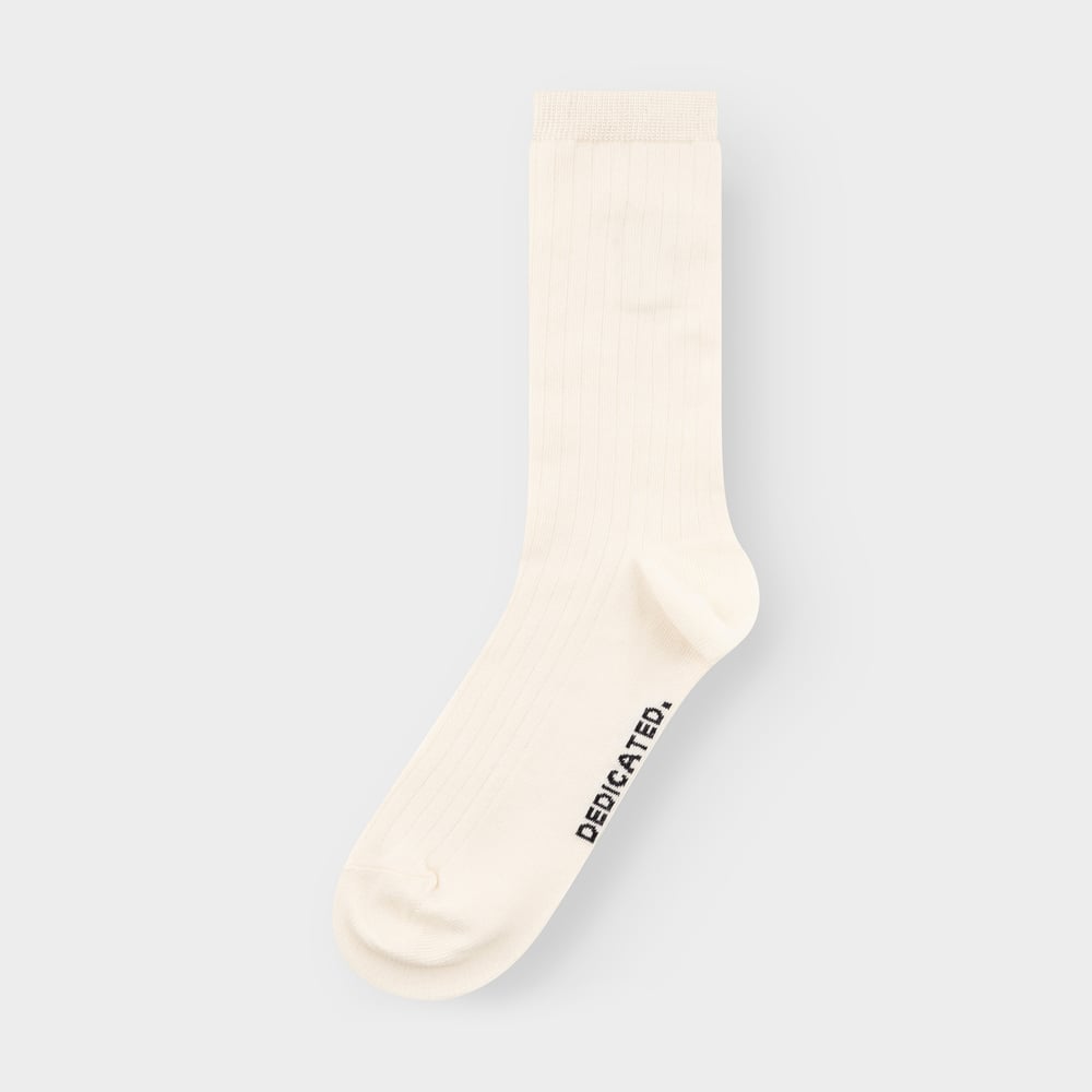 A single off-white ribbed sock, the Rib Socks Knivsta, from Dedicated, shown flat against a light grey background.