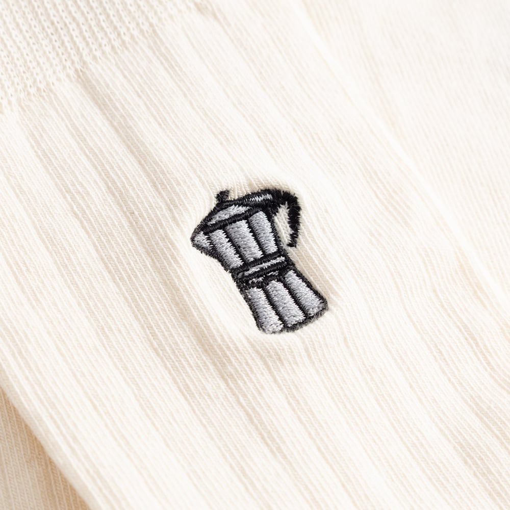 A detailed close-up of the small moka pot embroidered onto the ribbed fabric of the off-white Dedicated Knivsta socks.