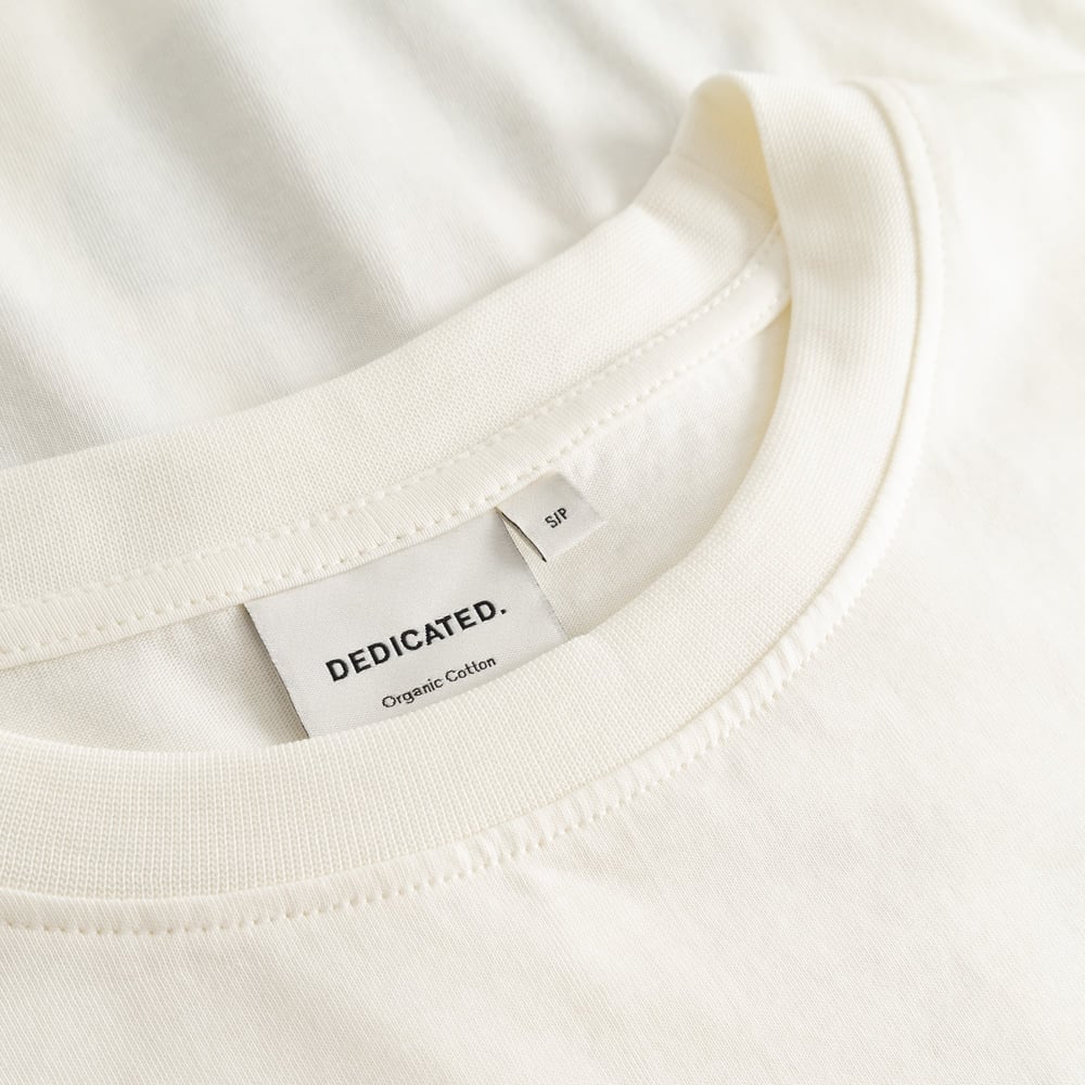 Close-up detail shot of the ribbed crew neck collar and brand label inside the off-white T-shirt Vadstena Autumn Harvest.