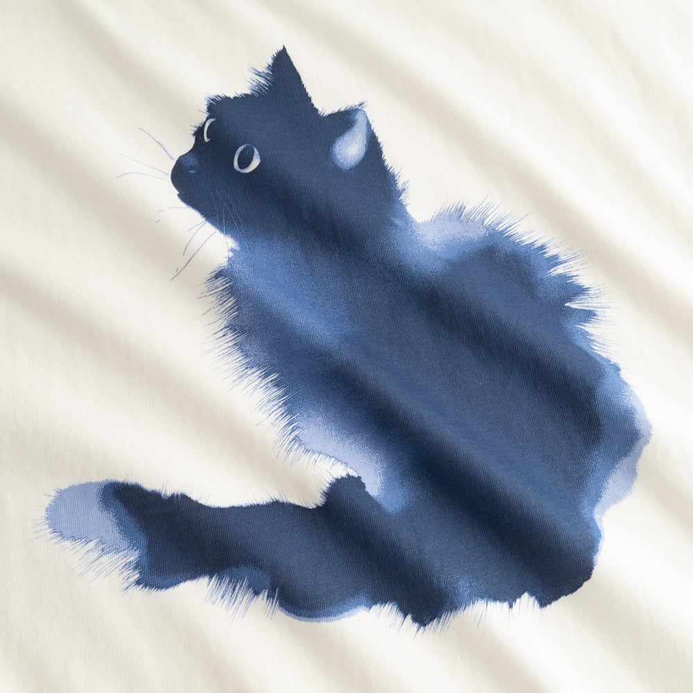 Close-up detail of the fluffy blue watercolor cat print on the off-white Visby T-shirt.