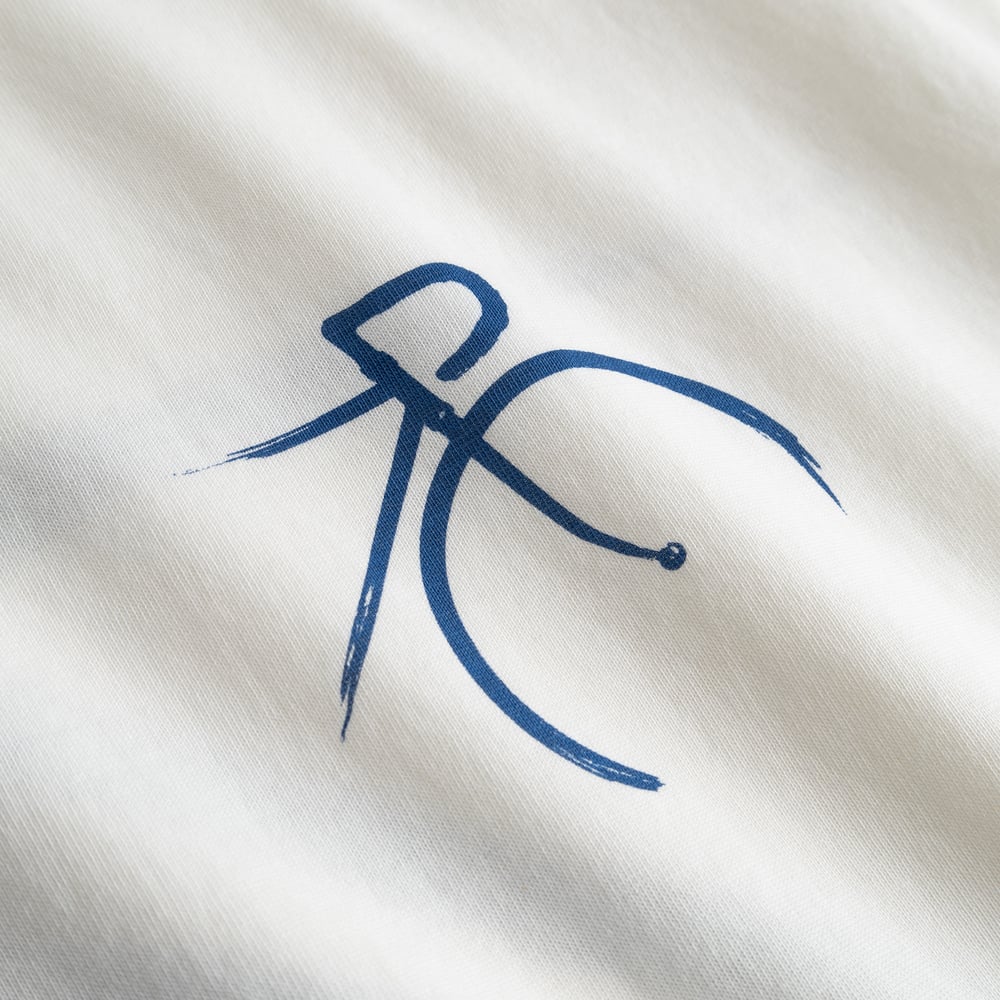 Close-up of the T-shirt Stockholm in Off-White, showing the artistic brush-stroke detail of the blue bicycle graphic.