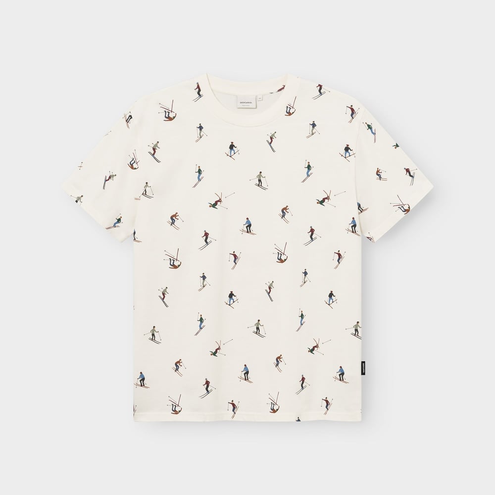 Flat lay of an off-white t-shirt with a fun all-over print featuring colorful illustrations of skiers.