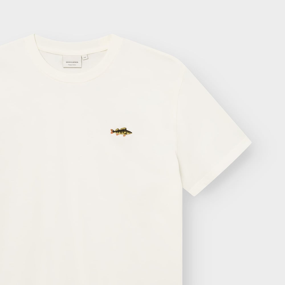 A close-up view of the off-white T-shirt Stockholm, showing the detailed perch embroidery and the Dedicated brand label.