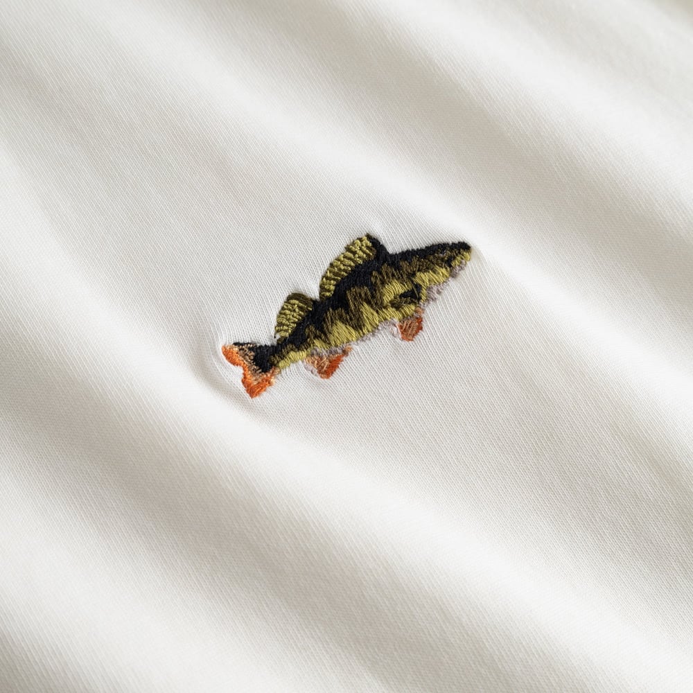 Close-up of the detailed, colourful perch embroidery on the soft fabric of our off-white Stockholm t-shirt.