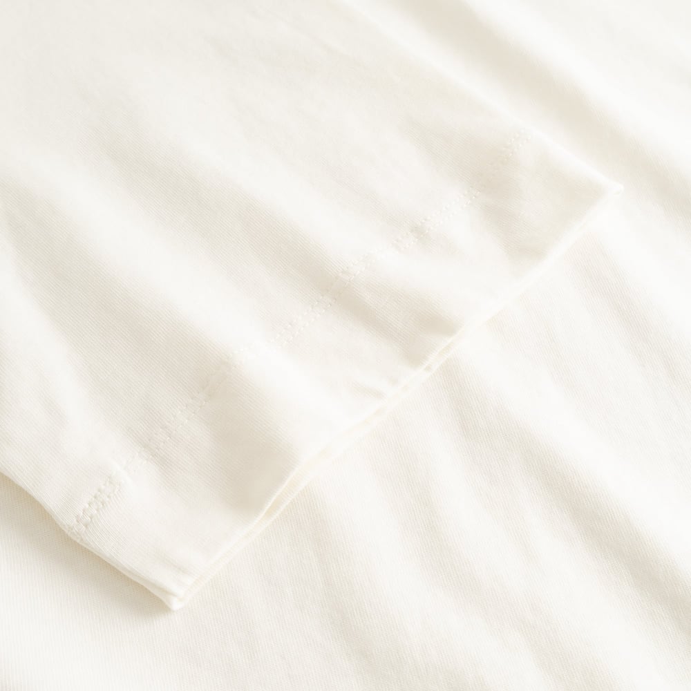 Close-up of the finely stitched sleeve on the T-shirt Vadstena in soft, off-white organic cotton.