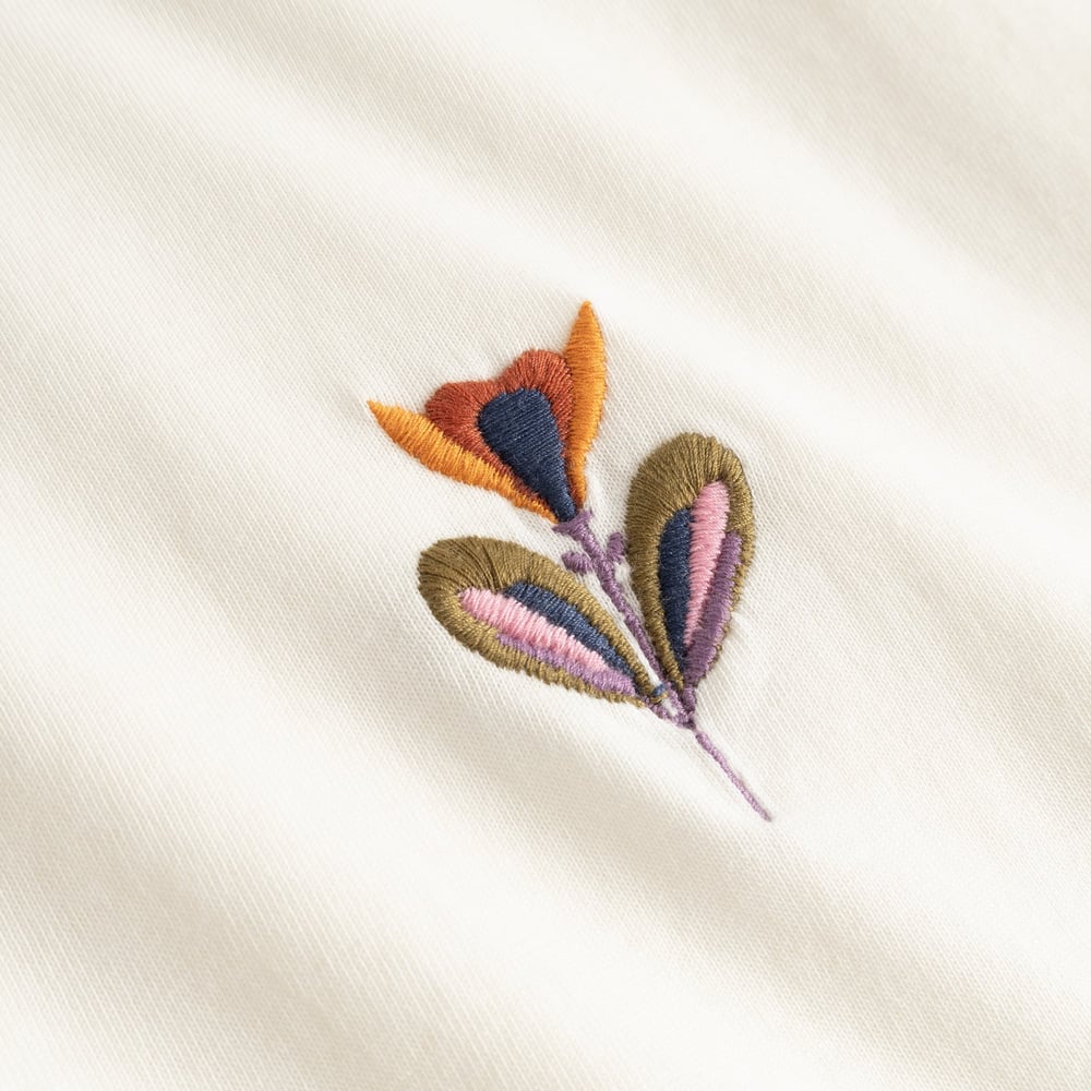 A detailed close-up of the lovely Autumn Harvest floral embroidery on the off-white Vadstena T-shirt.