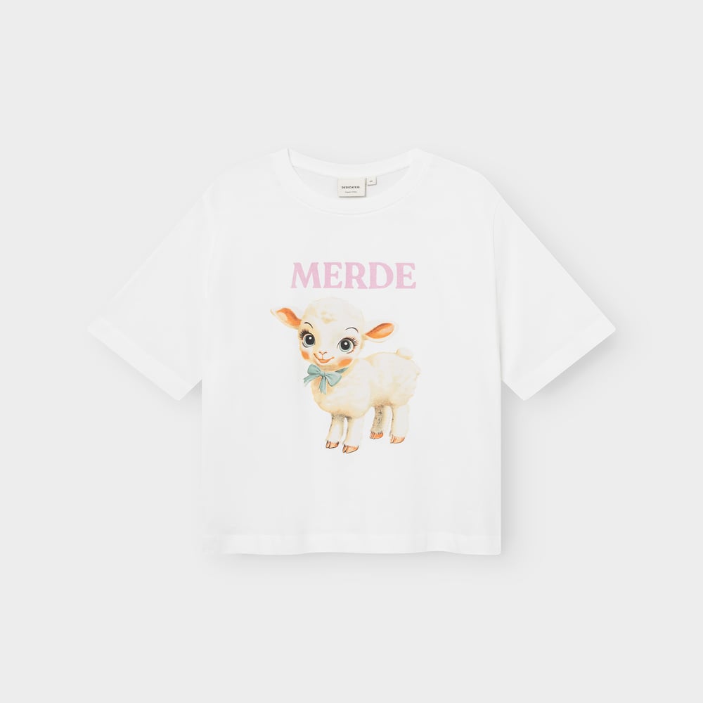 Flat lay of the white Vadstena t-shirt with a playful print of a cute lamb and the word 'MERDE' in pink.