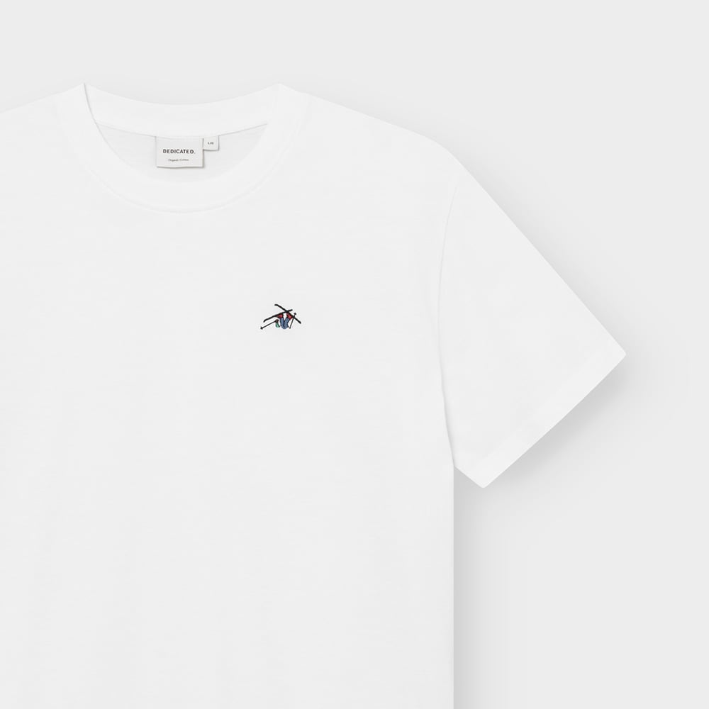 Close-up of the white T-shirt Stockholm Ski Crash, showing the playful skier embroidery on the chest and the brand label.