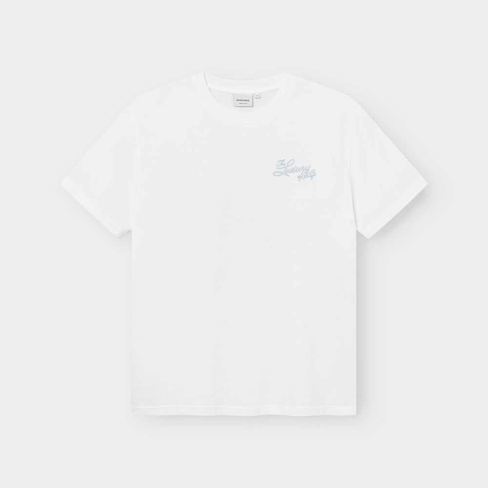 The classic white Stockholm T-shirt featuring 'The Luxury of Fondue' in a light blue script on the chest.