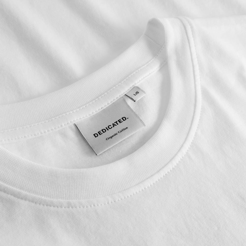 Close-up of the Dedicated brand label and ribbed collar on the T-shirt Stockholm Fondue White.