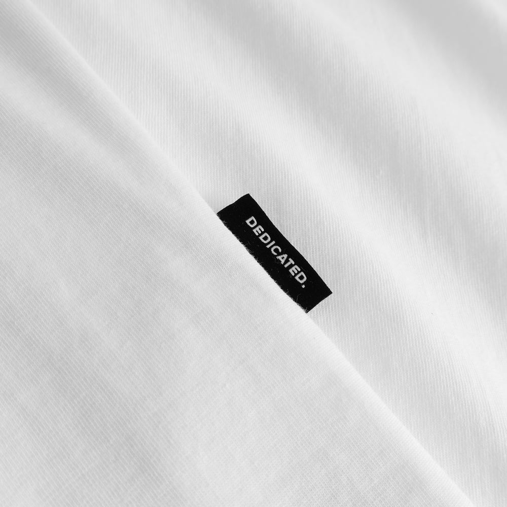 Close-up on the white T-shirt Stockholm Monday Crash, featuring the black Dedicated brand tab on the seam.