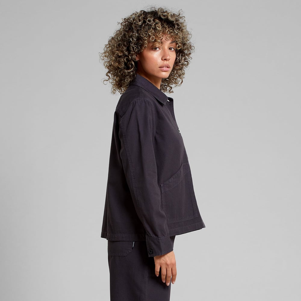 A model with curly hair looks over her shoulder, showing the side view of the Stiby Canvas Jacket in Phantom Black.