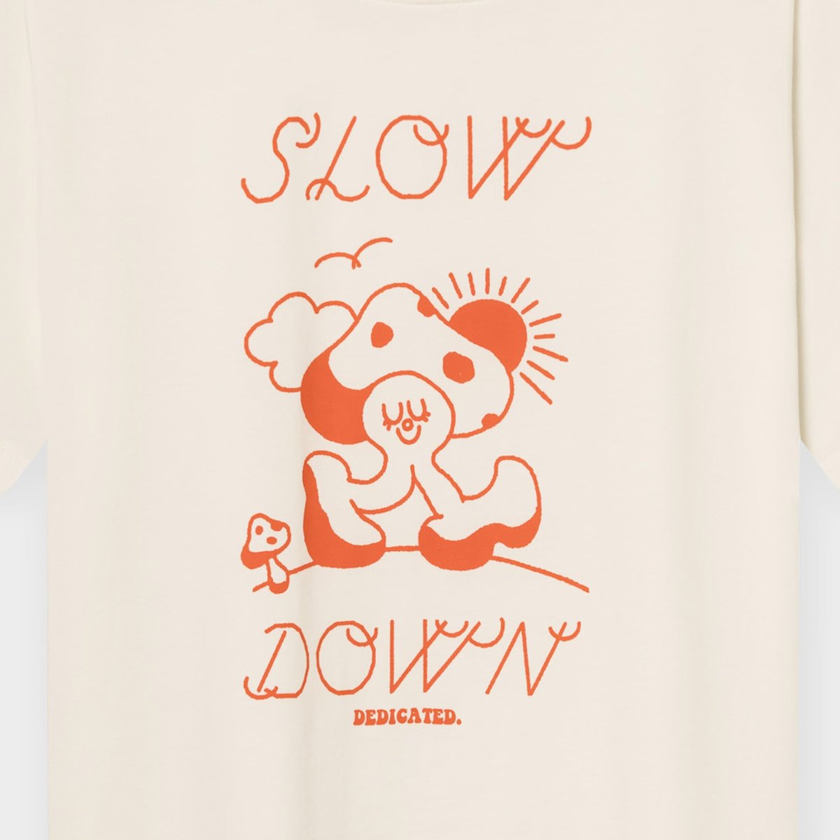 Närbild på den benvita T-shirten Vadstena Slow Down med det orangea grafiska trycket 'Slow Down' och en svampfigur.