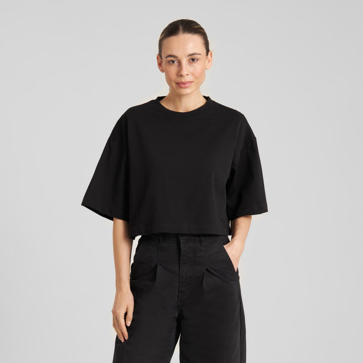 Front view of a model in the black cropped T-shirt Ljusdal, styled with black pants for a cool, monochrome outfit.