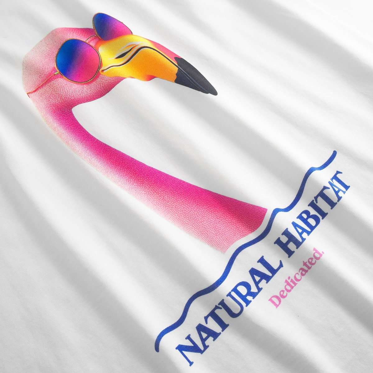 Close-up of the fun 'Beach Habitat' print, featuring a pink flamingo in sunglasses on an off-white tee.