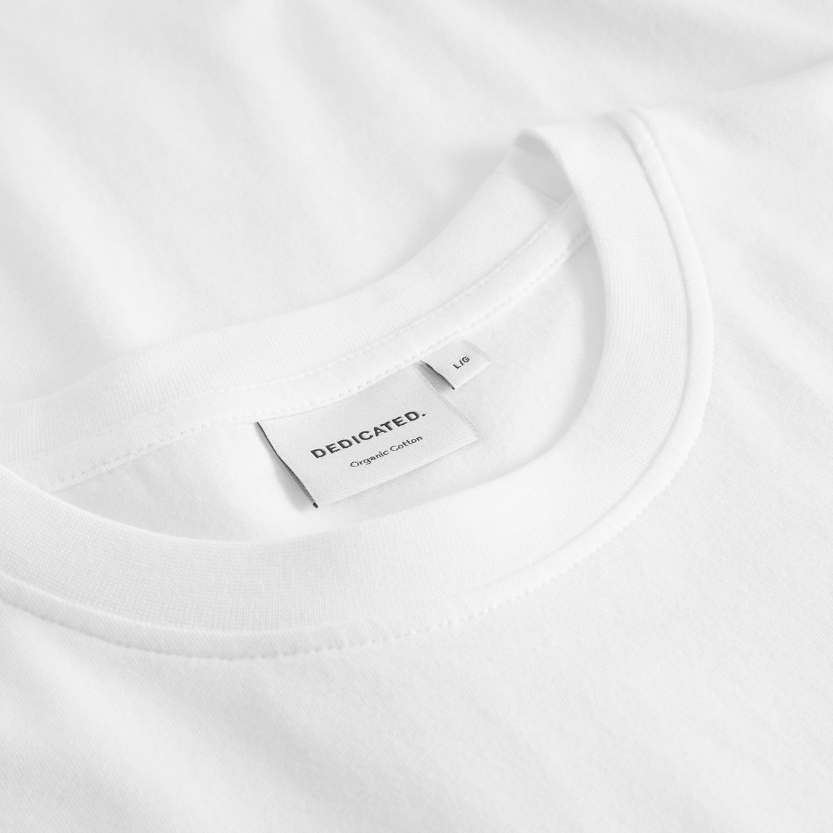 Nahaufnahme des Kragens und Markenetiketts des weißen T-Shirts Stockholm Pour Some White aus Bio-Baumwolle.