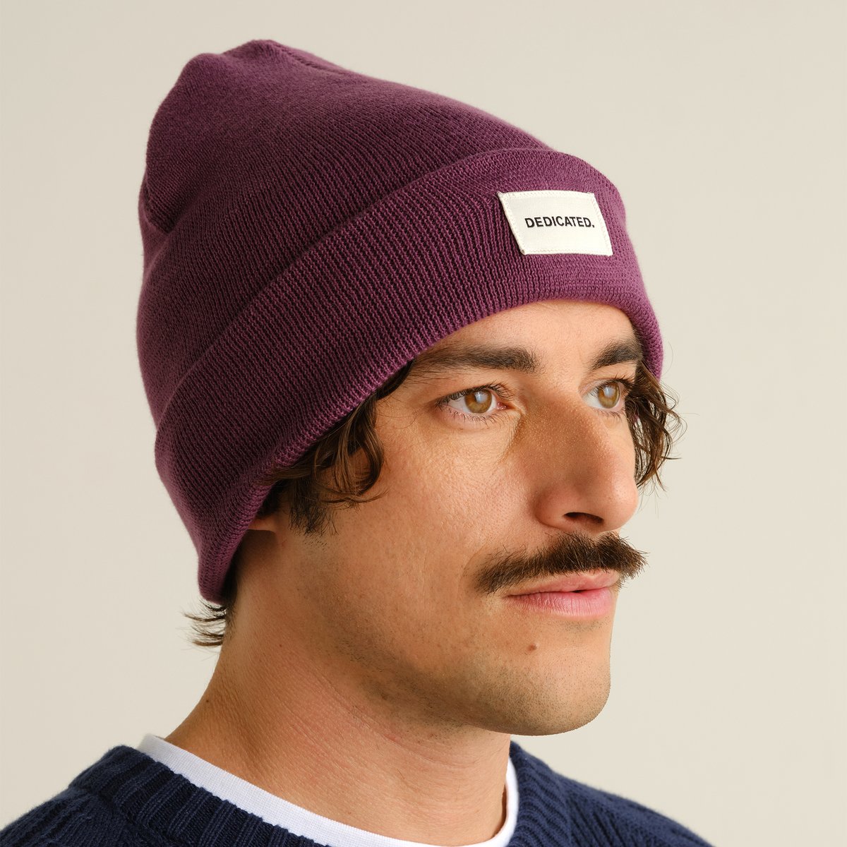 Närbild på en man med mustasch som bär den bärlila mössan Kiruna.