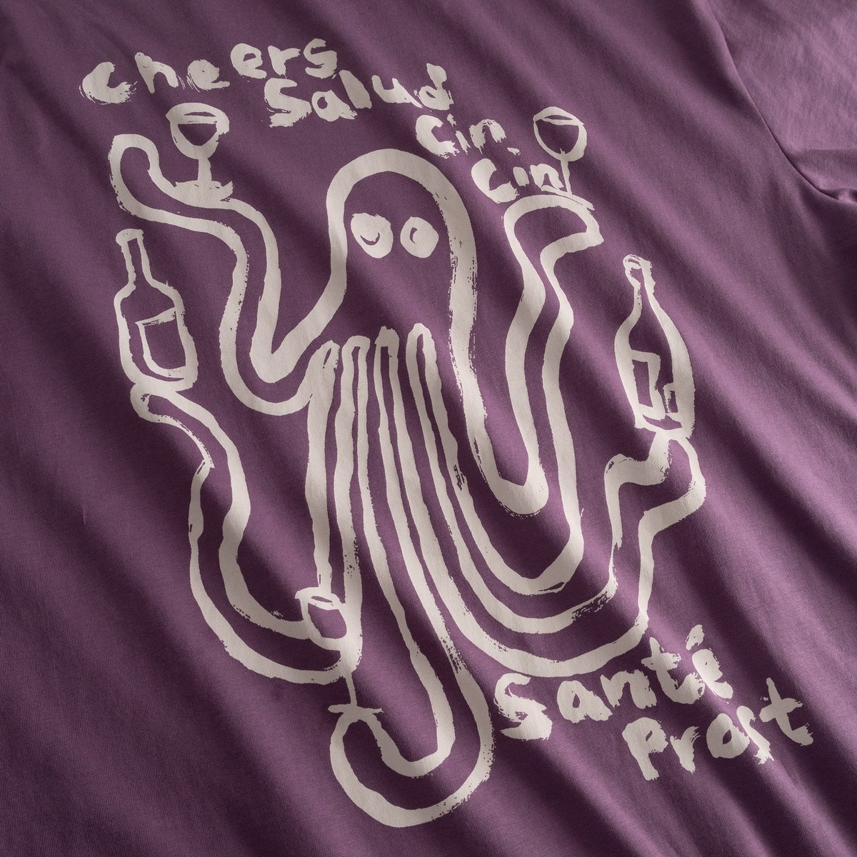 Nahaufnahme des verspielten Oktopus-Prints auf dem lila T-Shirt Stockholm Cheers Salud.