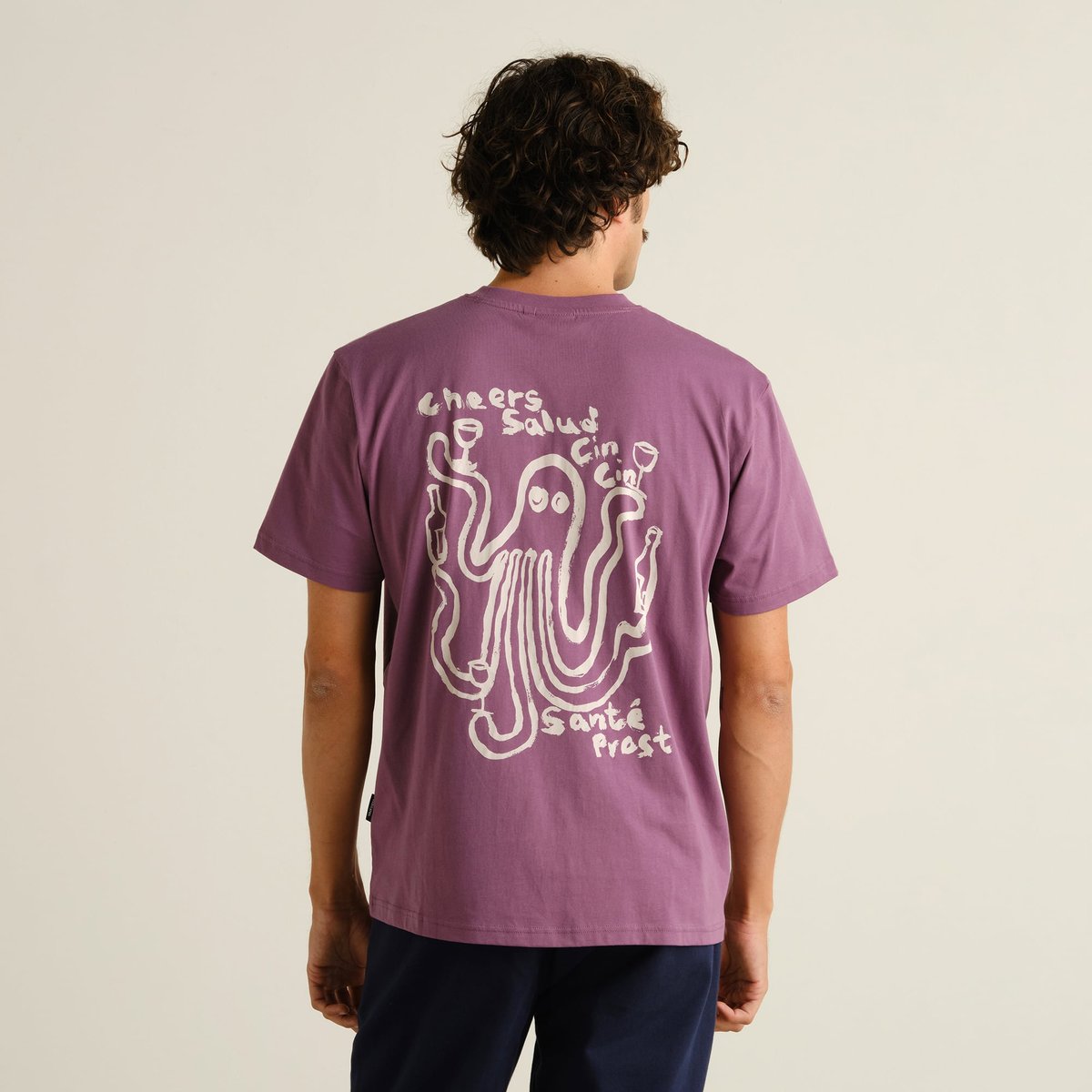 Das T-Shirt 'Cheers Salud' in Beerenlila, von hinten an einem Model getragen, mit verspieltem Oktopus-Print.