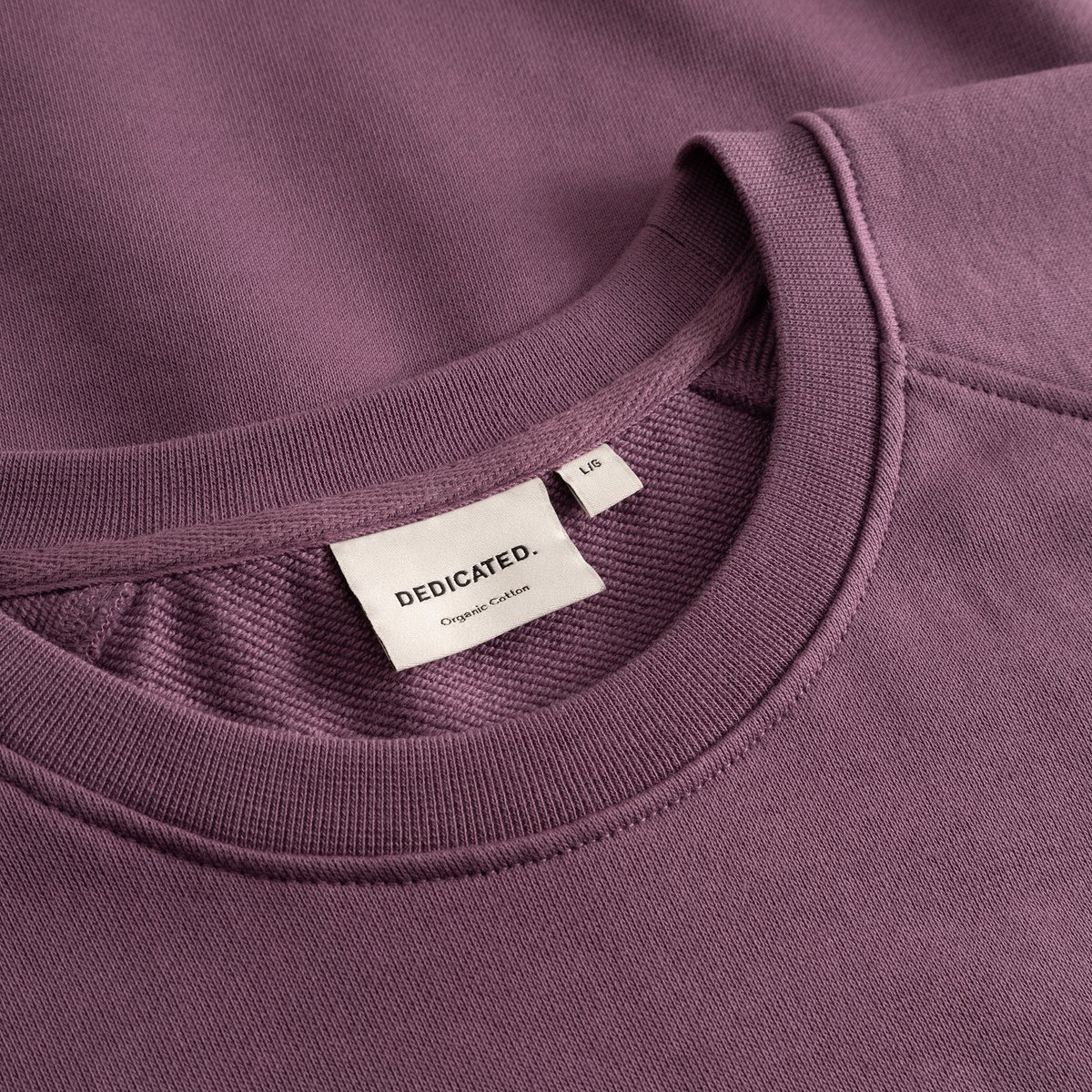 Close-up shot of the Sweatshirt Malmoe Base in Berry Purple, focusing on the ribbed crew neck and the Dedicated brand label.