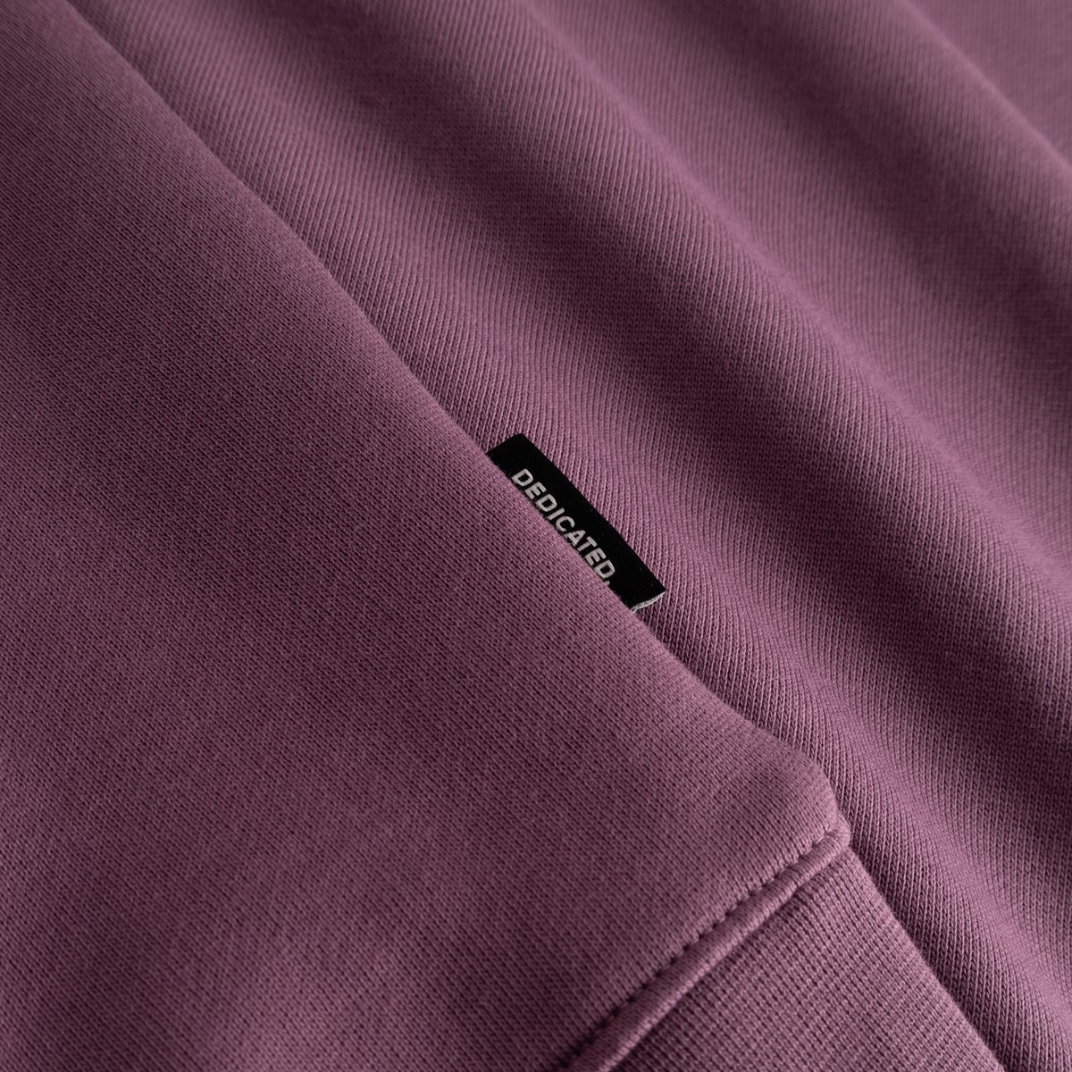 Close-up of the Sweatshirt Malmoe Base in Berry Purple, showing the soft organic cotton and the black Dedicated brand tag.