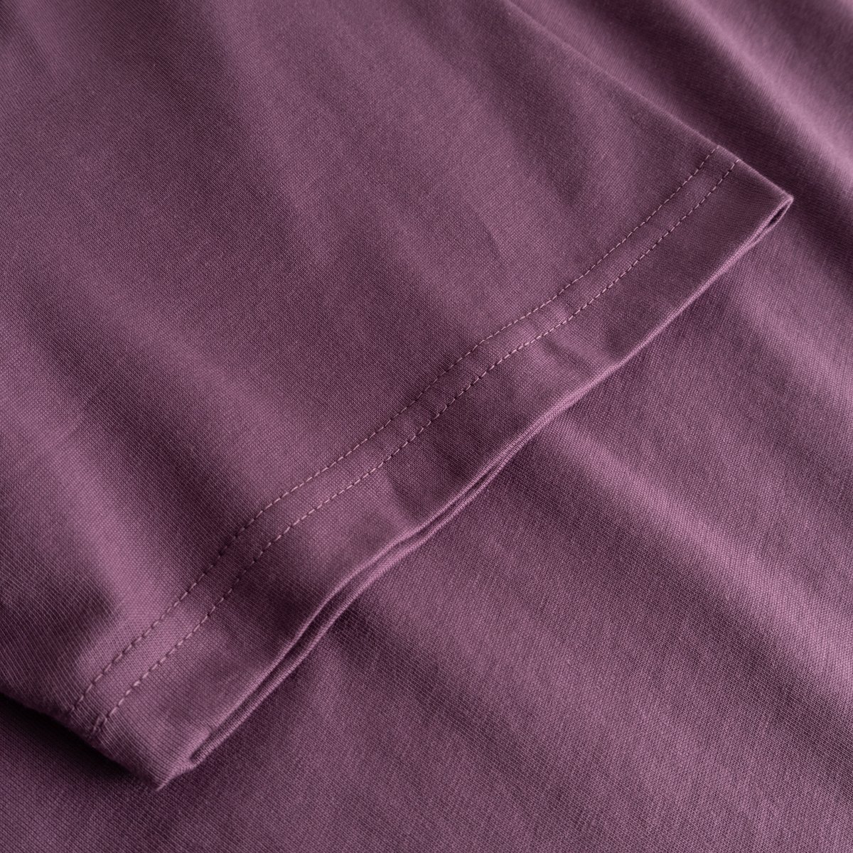 Närbild på ärmen på T-shirt Stockholm Base Berry Purple, som visar tygets struktur och sömmar.
