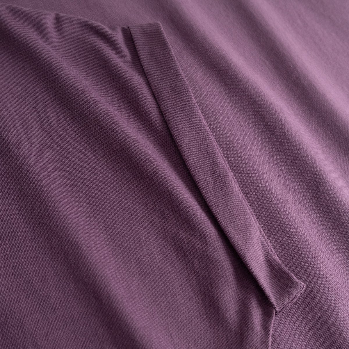 A detailed look at the folded sleeve of our T-shirt Visby Base in Berry Purple, crafted from soft organic cotton.