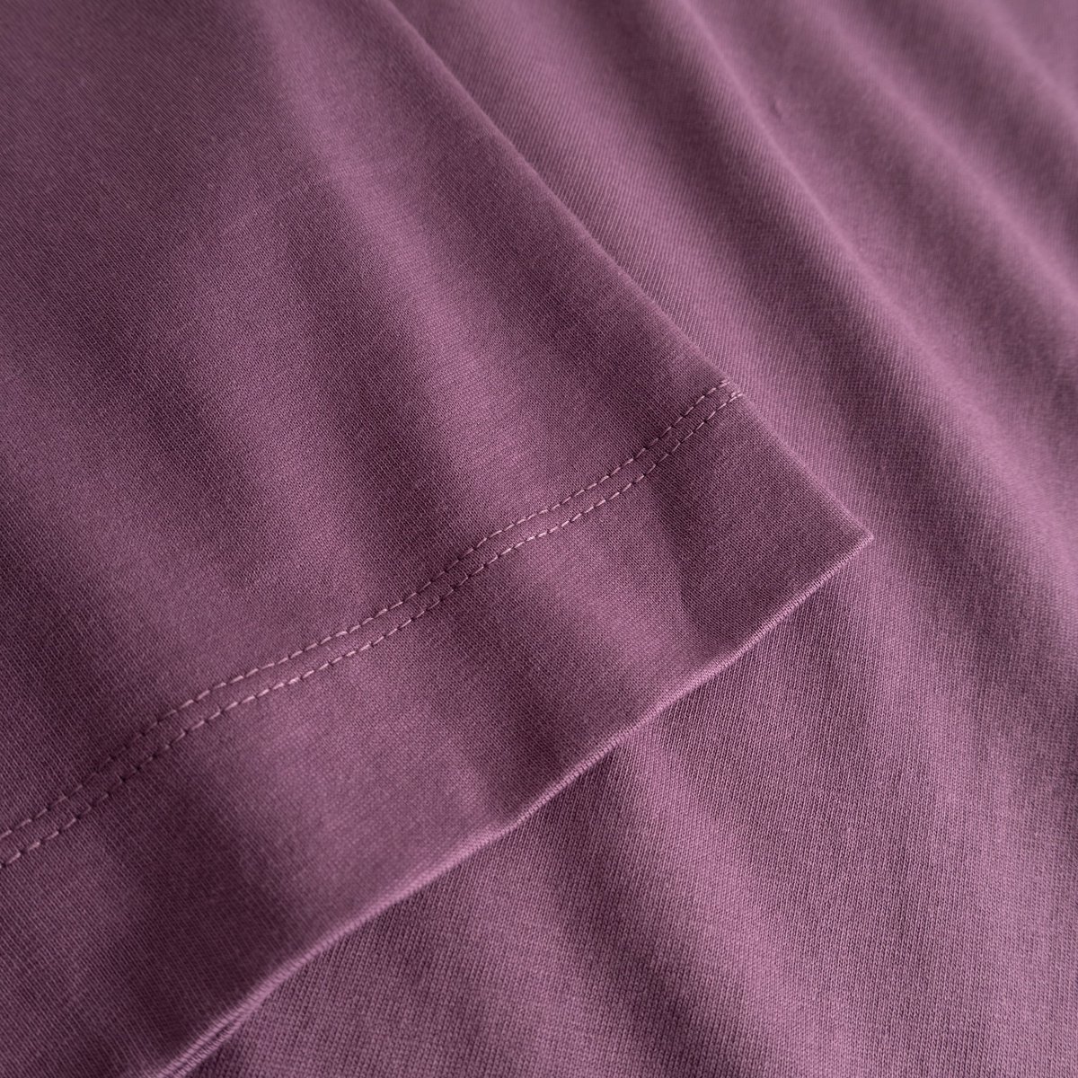A close-up of the T-shirt Vadstena Base in Berry Purple highlighting the soft organic cotton and the sleeve's fine stitching.