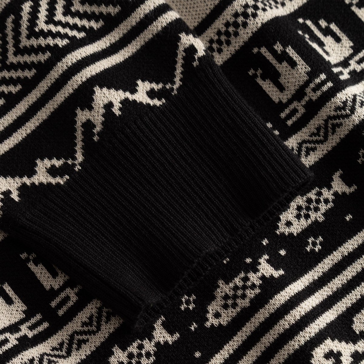 Close-up on the sleeve of the black Sweater Mora Fairisle Hike, showing the fine ribbed cuff and detailed jacquard knit.