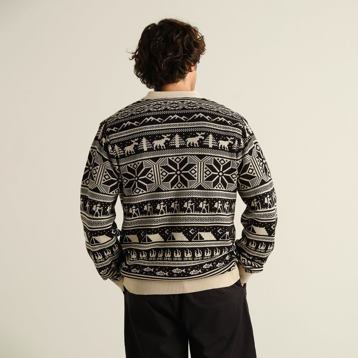 The Cardigan Delsbo Fairsle Hike Black, seen from behind on a model, revealing its fun and intricate jacquard pattern.