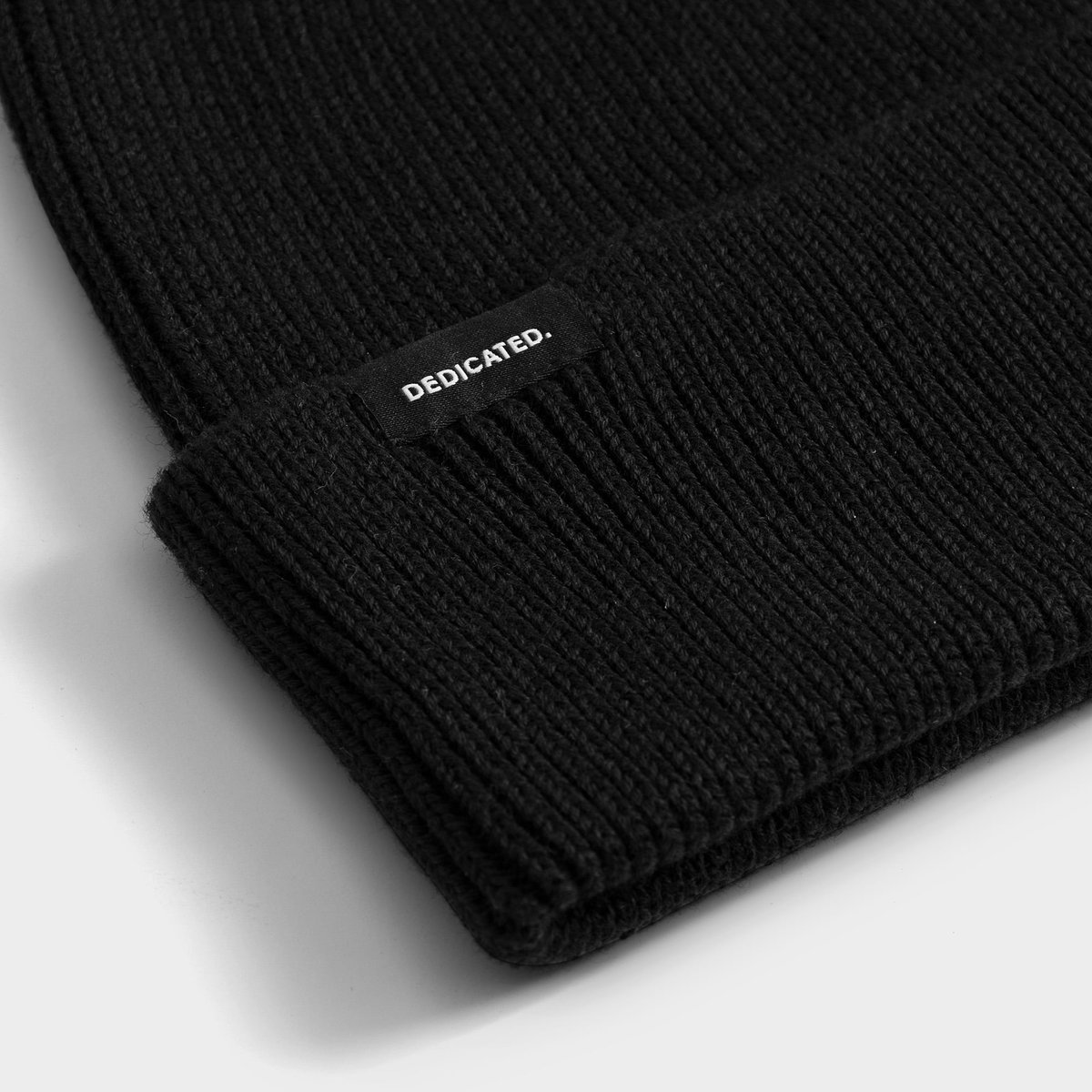 A detailed close-up of the black Beanie Hemavan, showing its chunky ribbed knit and the signature Dedicated logo label.