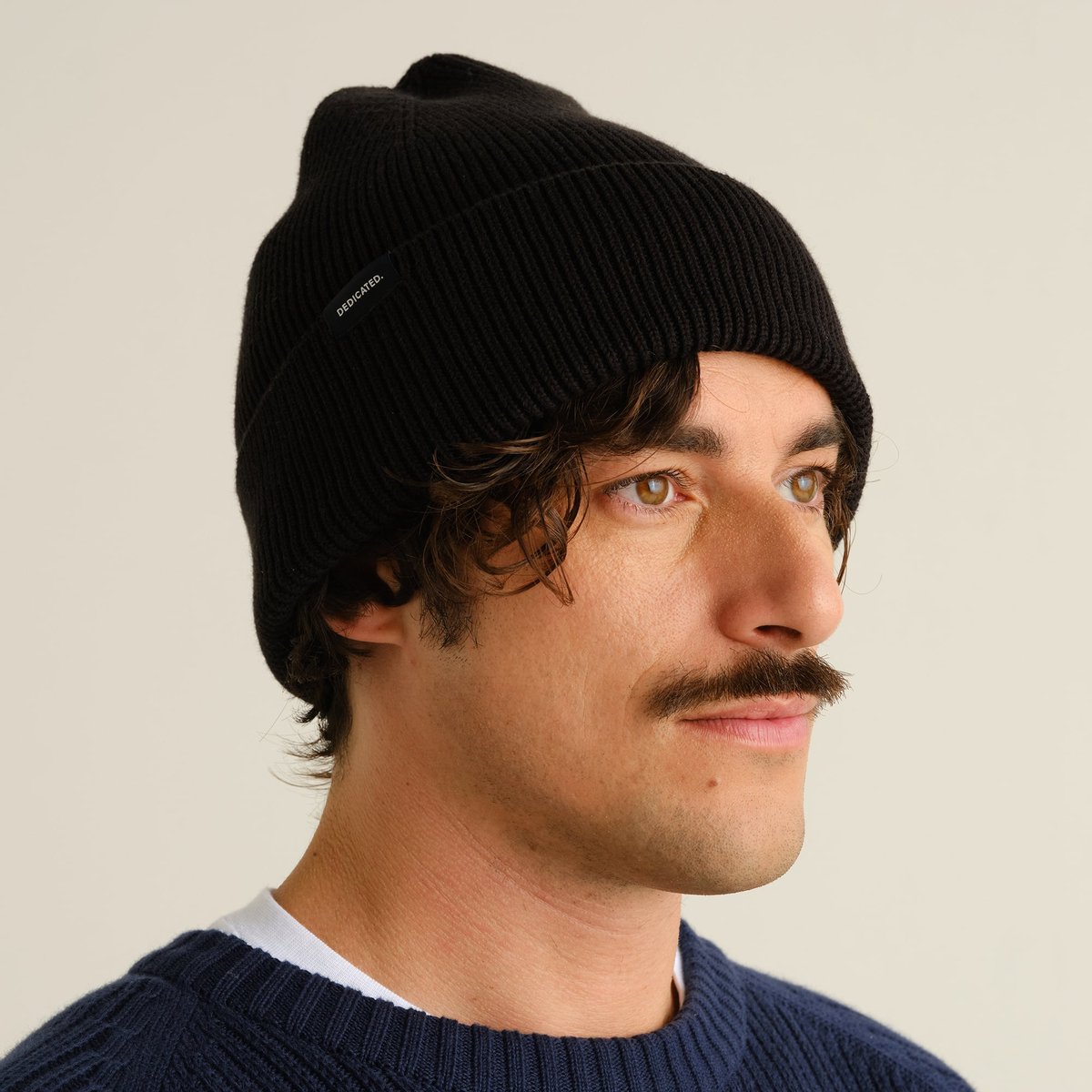 A man with a mustache wearing the black, chunky-knit Beanie Hemavan.