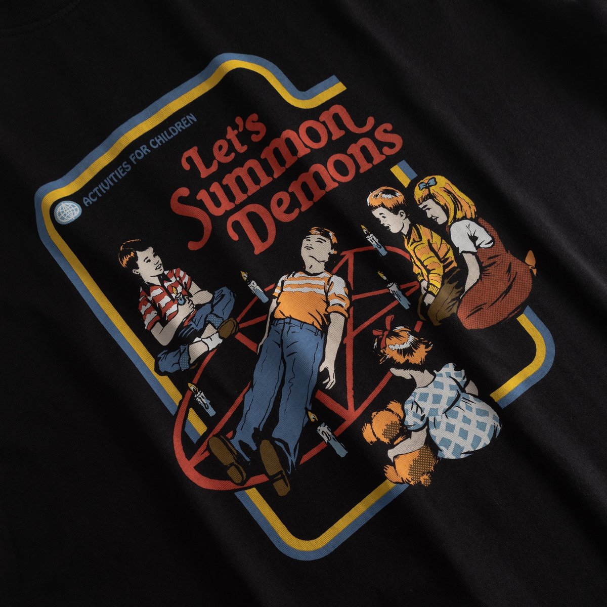 Close-up of the retro 'Let's Summon Demons' print by Steven Rhodes on a black t-shirt.