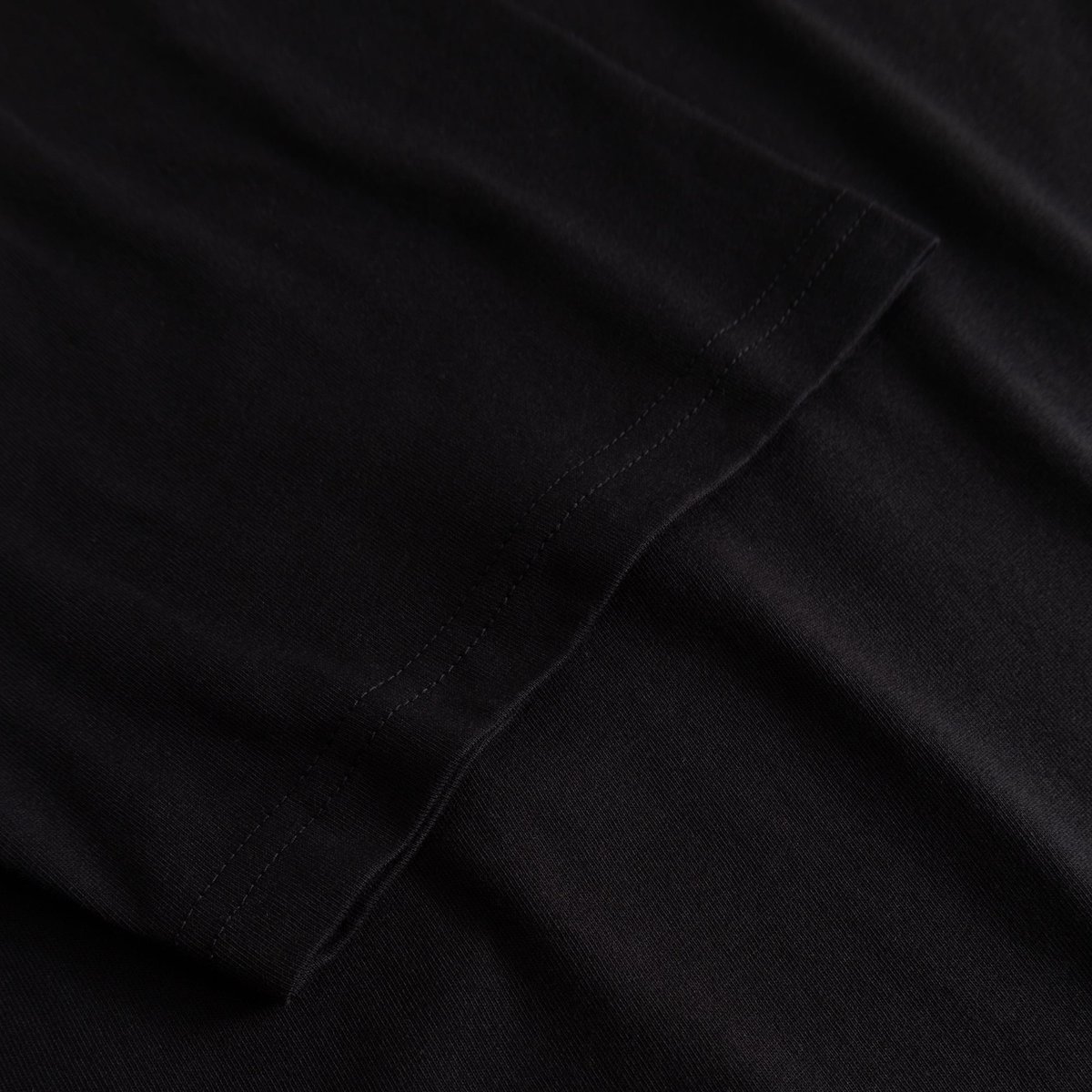 Close-up of the finely stitched sleeve on the T-shirt Stockholm My Imaginary Friends in black.