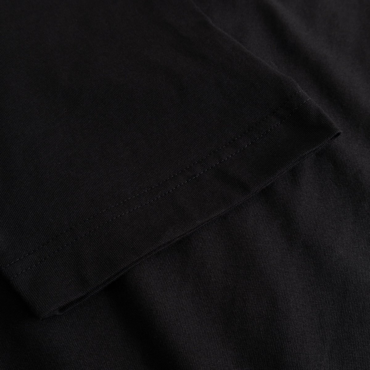 Close-up of the sleeve hem on the black organic cotton T-shirt Vadstena, highlighting the double-needle stitching detail.
