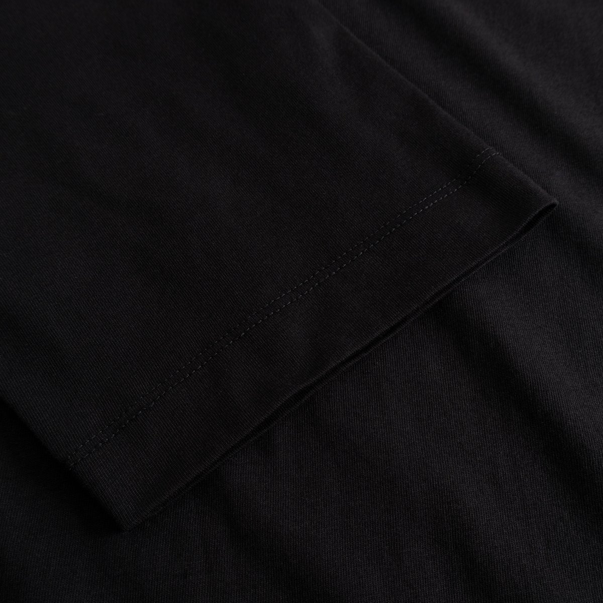 Close-up of the sleeve detail on the T-shirt Vadstena Hanging With All My Friends, showing the soft black organic cotton.
