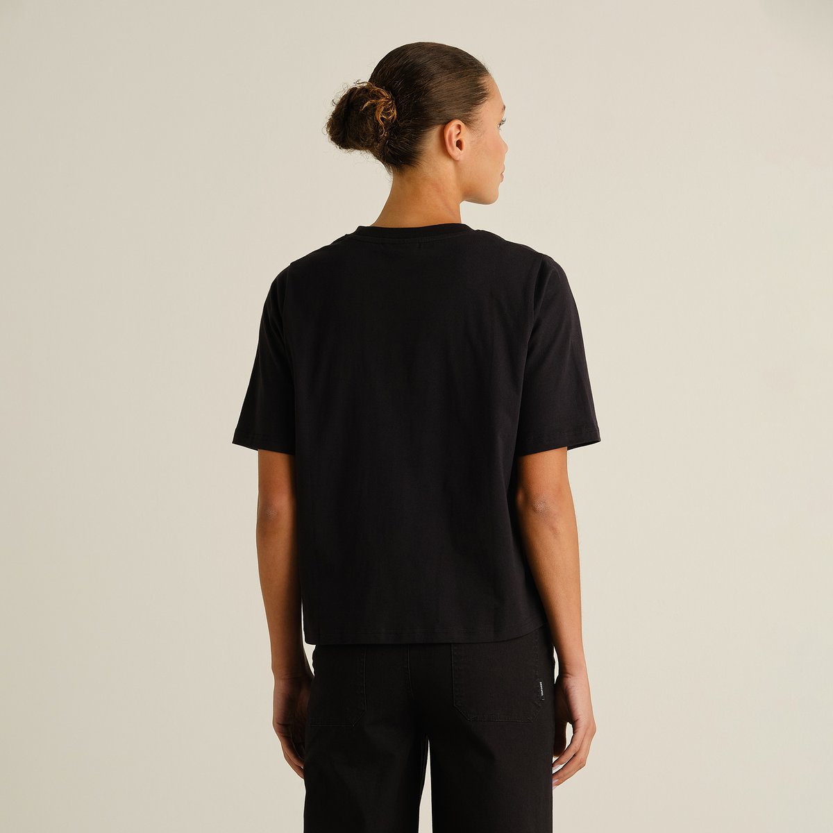 A woman seen from behind wearing the T-shirt Vadstena Painted Swans in black.